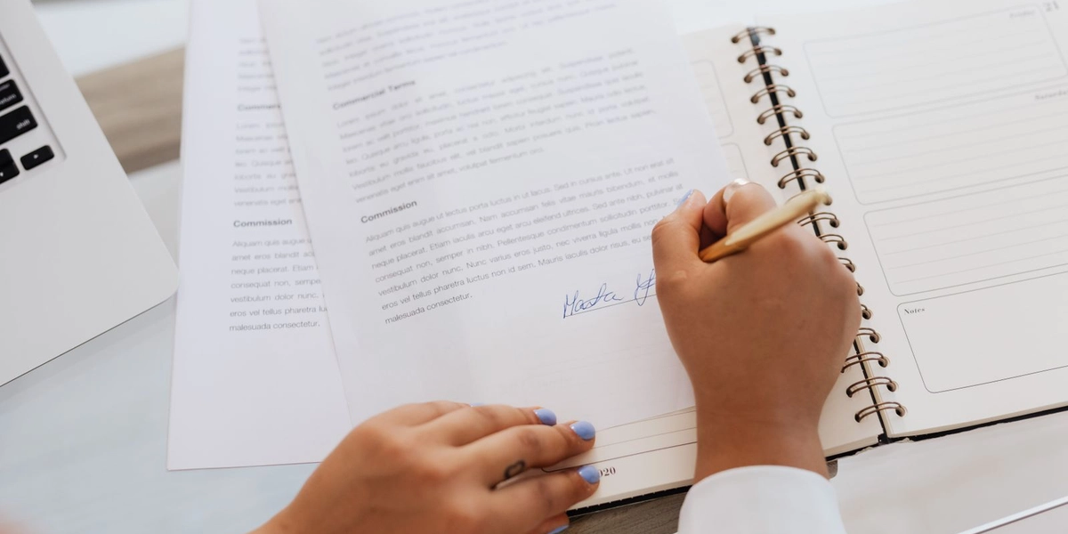 A person reviewing and signing a contract at a desk