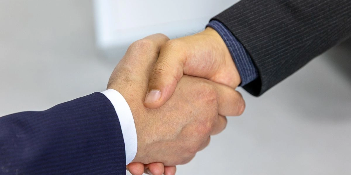 Two business professionals shaking hands, representing a teaming partnership