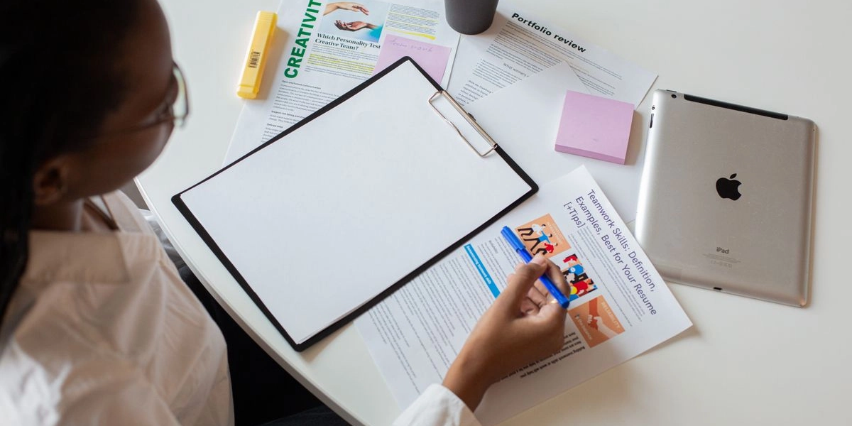 A person reviewing a company portfolio and resume documents at a desk