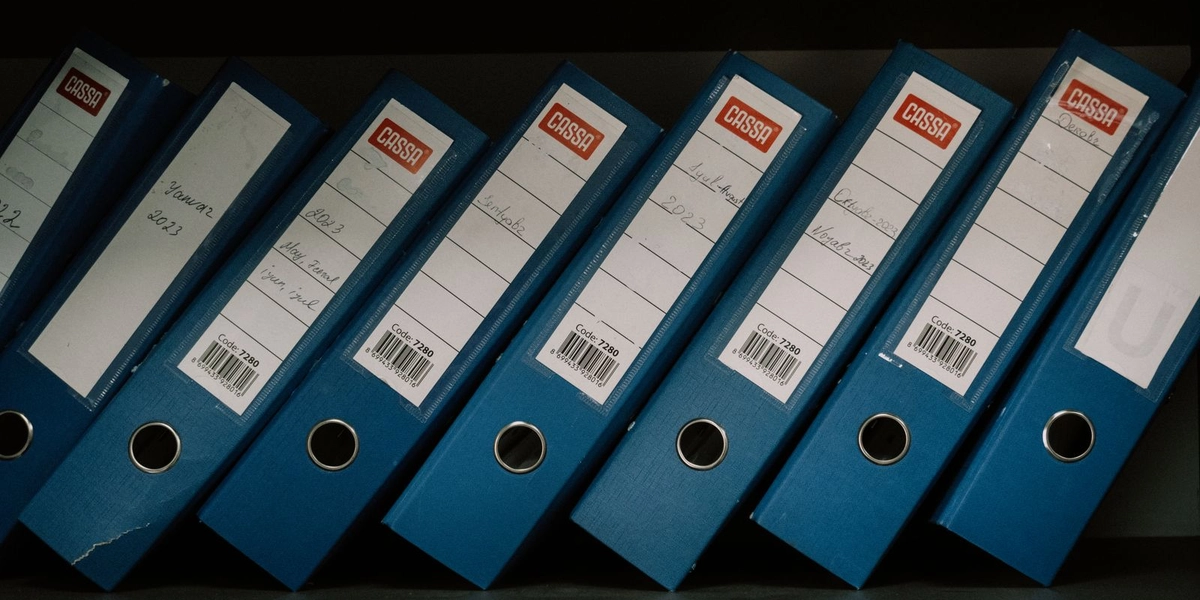 Rows of organized blue file binders on a shelf